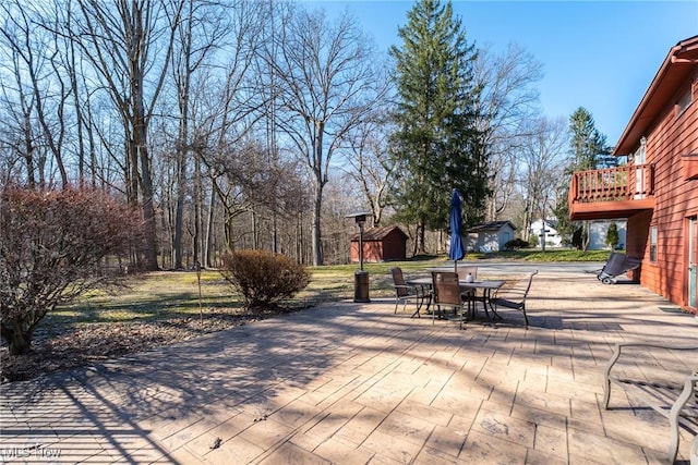 view of patio / terrace featuring outdoor dining space, a shed, and an outdoor structure