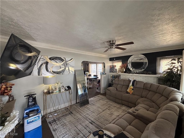 living room with a textured ceiling, a ceiling fan, and ornamental molding