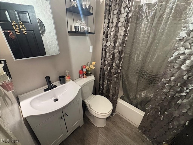 bathroom featuring toilet, shower / bathtub combination with curtain, vanity, and wood finished floors