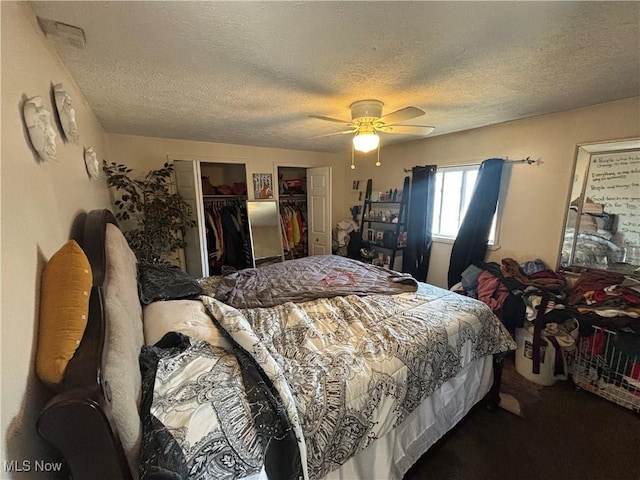 bedroom featuring carpet flooring, a textured ceiling, two closets, and a ceiling fan