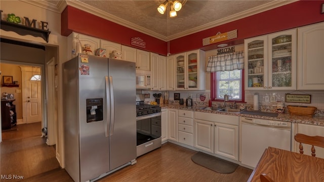 kitchen with a sink, wood finished floors, appliances with stainless steel finishes, and ornamental molding