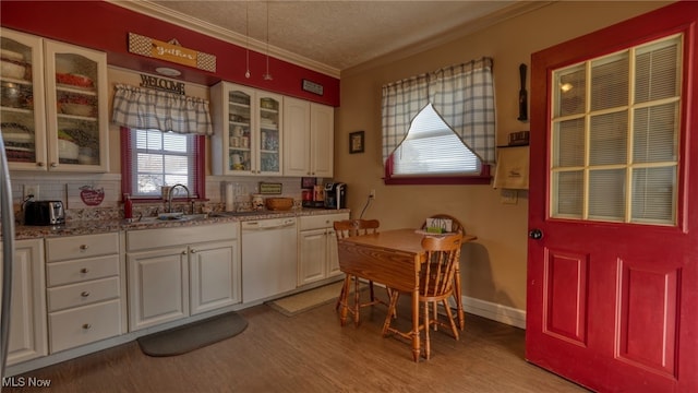 kitchen with a sink, light wood-style flooring, crown molding, and white dishwasher