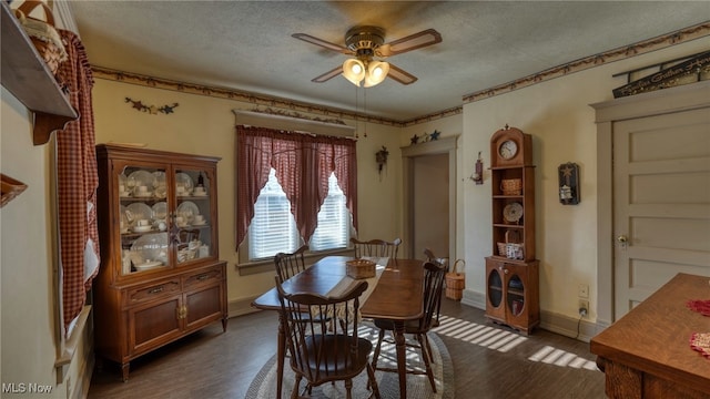 dining space featuring baseboards, a textured ceiling, dark wood finished floors, and a ceiling fan