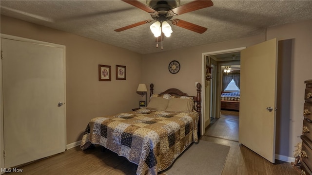 bedroom with baseboards, a textured ceiling, and wood finished floors