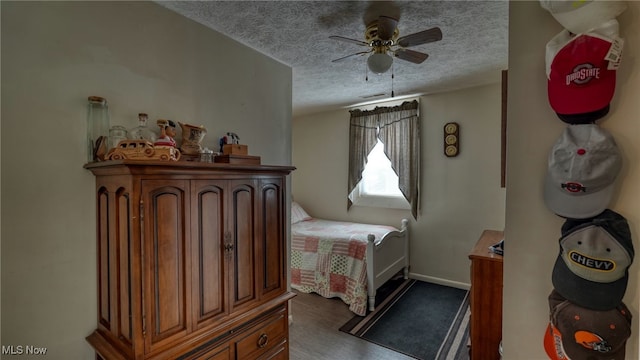 bedroom featuring ceiling fan, wood finished floors, baseboards, and a textured ceiling