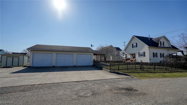 view of front facade featuring an outdoor structure, a storage unit, fence, and a garage