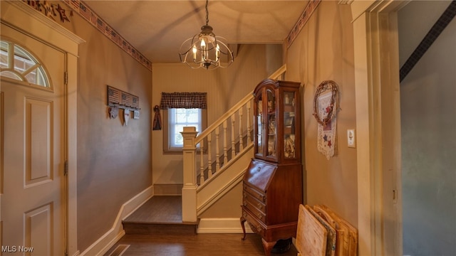 entryway featuring baseboards, an inviting chandelier, dark wood finished floors, and stairs