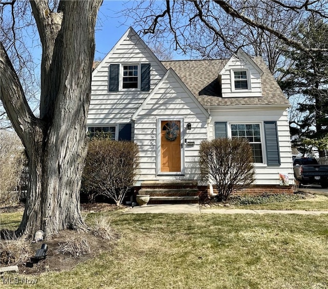 cape cod home featuring a shingled roof, a front lawn, and entry steps