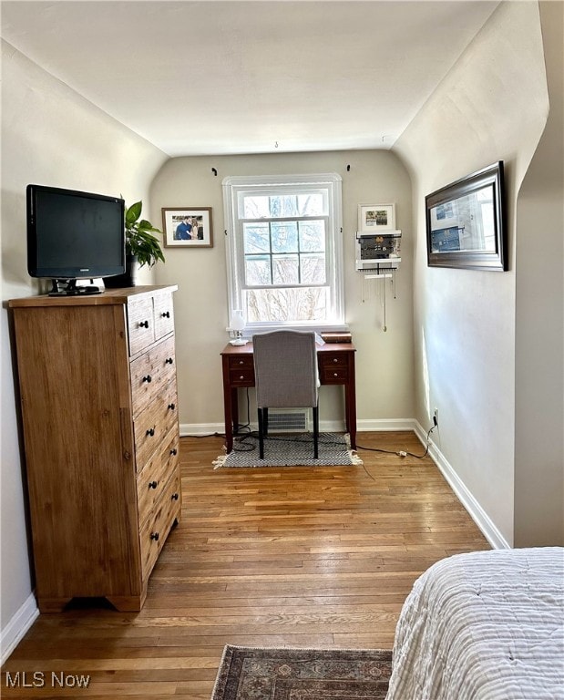 bedroom featuring hardwood / wood-style floors, lofted ceiling, and baseboards