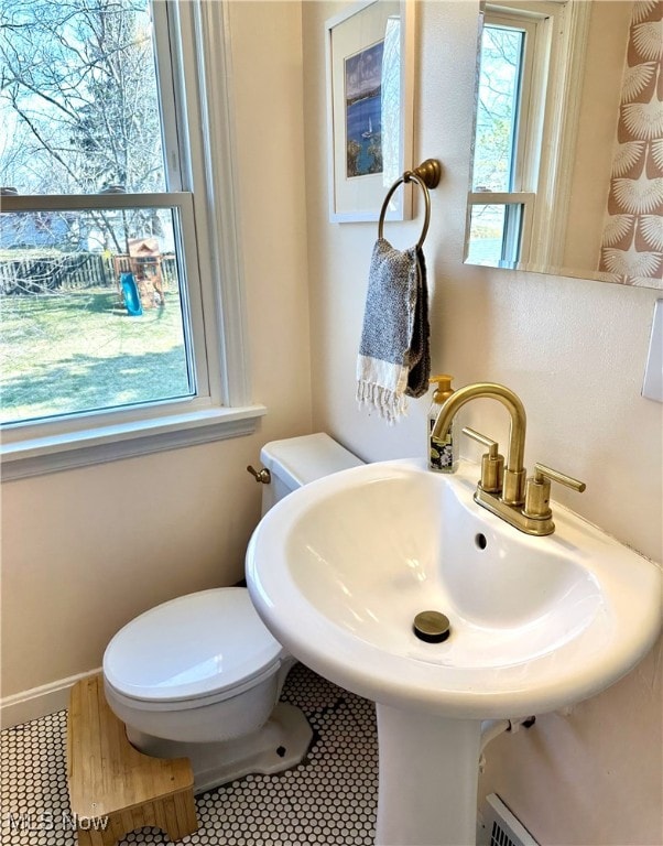 bathroom featuring tile patterned flooring, toilet, baseboards, and a sink