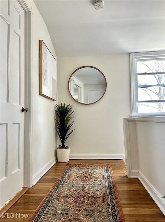 hallway with lofted ceiling, baseboards, and wood finished floors