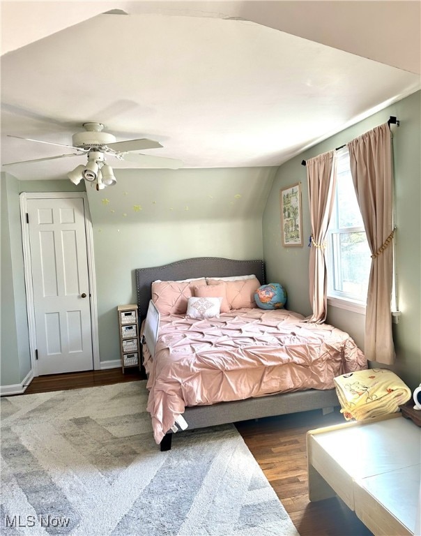 bedroom featuring a ceiling fan, vaulted ceiling, wood finished floors, and baseboards