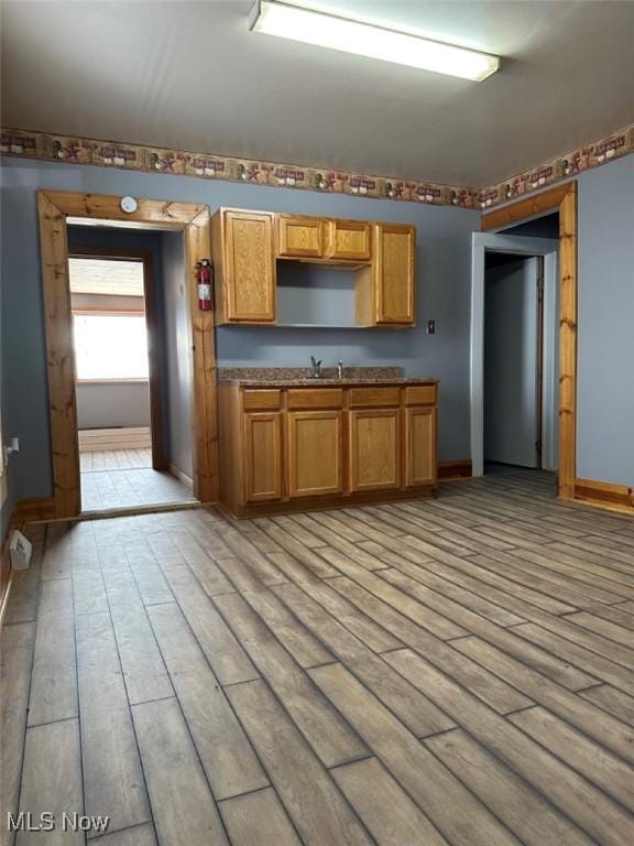 2046 Ohio Ave, East Liverpool, OH 43920 - kitchen featuring baseboards, brown cabinetry, light wood-type flooring, and a sink