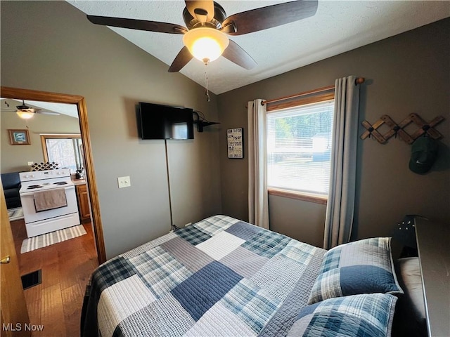 bedroom featuring vaulted ceiling, wood finished floors, visible vents, and ceiling fan