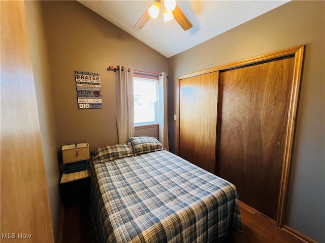 bedroom with ceiling fan, a closet, lofted ceiling, and wood finished floors