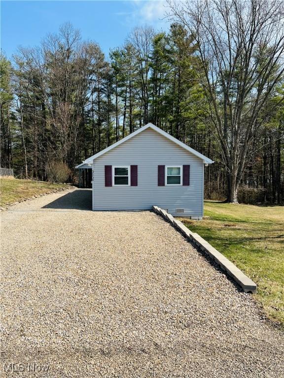 exterior space with gravel driveway, a lawn, and crawl space