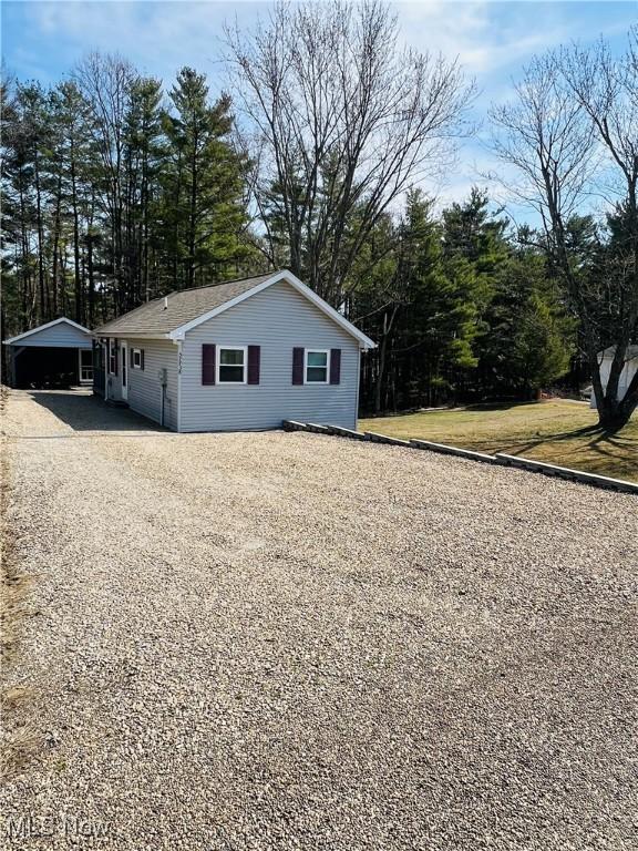 view of home's exterior featuring gravel driveway and a carport