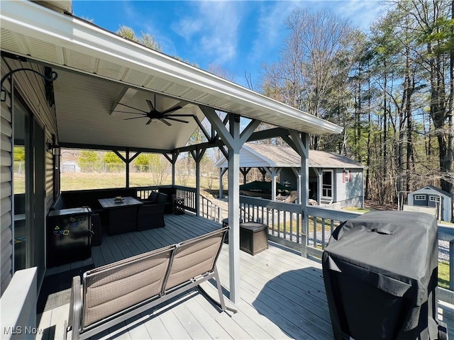 wooden terrace with a gazebo, an outbuilding, a grill, and ceiling fan