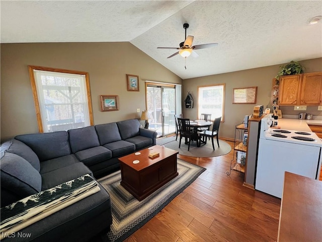 living room featuring ceiling fan, lofted ceiling, a textured ceiling, and wood finished floors