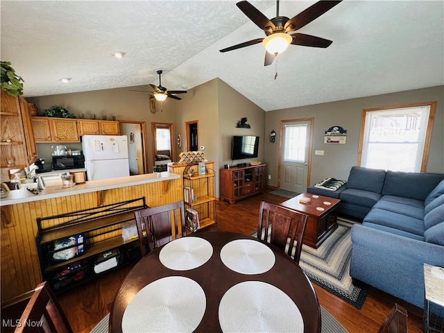 dining area featuring wood finished floors, a textured ceiling, ceiling fan, and vaulted ceiling