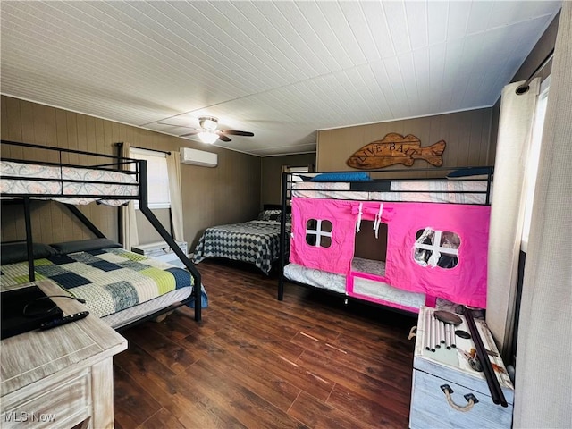 bedroom featuring wooden walls, an AC wall unit, wood finished floors, and a ceiling fan