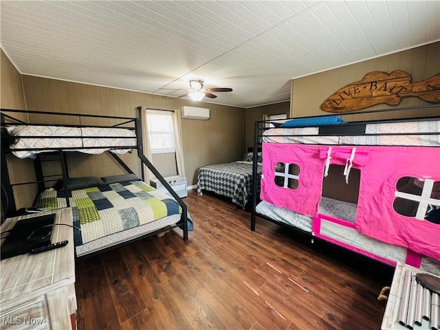 bedroom with a ceiling fan, wood finished floors, wood walls, and a wall mounted AC