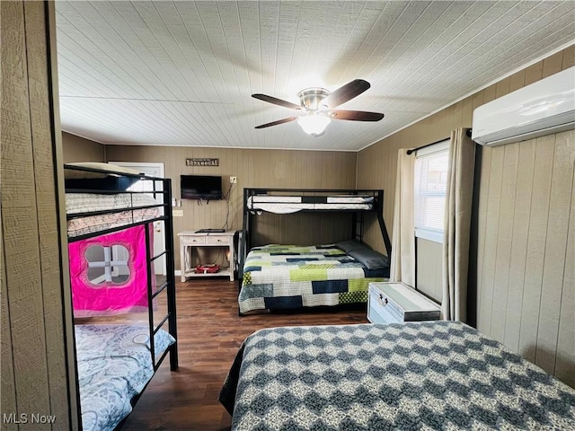 bedroom with wood walls, a wall mounted air conditioner, ceiling fan, and wood finished floors