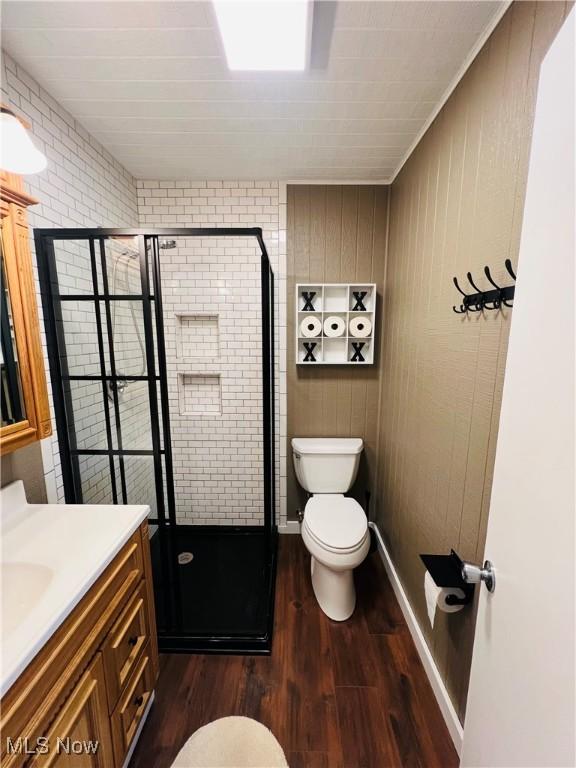 full bath with wood finished floors, toilet, a stall shower, and vanity