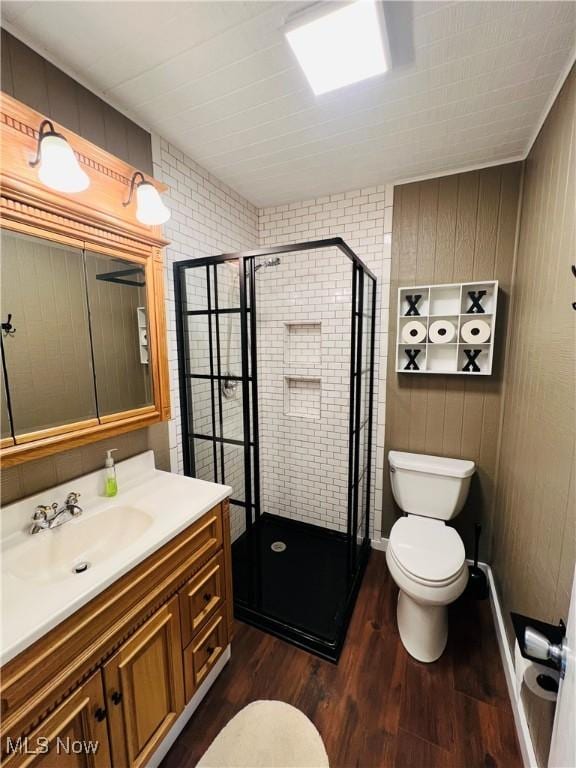 full bath with vanity, toilet, wood finished floors, and a stall shower