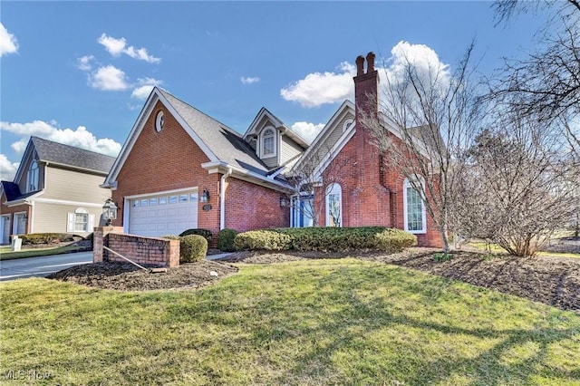 view of front facade with brick siding, a front yard, a chimney, a garage, and driveway