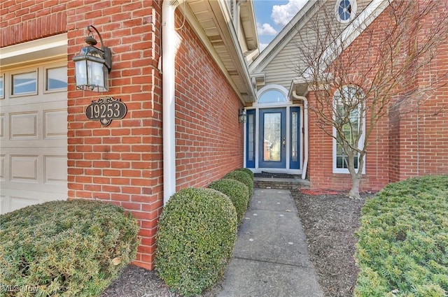 doorway to property with a garage and brick siding