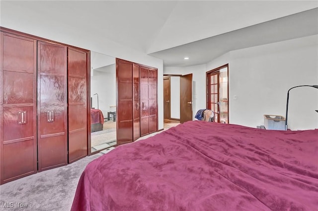 carpeted bedroom featuring vaulted ceiling and two closets