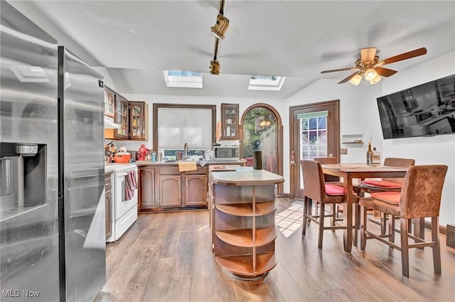 kitchen with a sink, open shelves, light wood finished floors, and stainless steel appliances