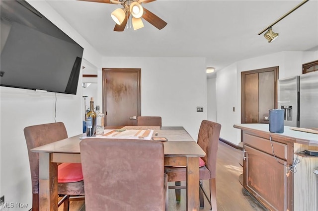 dining room featuring rail lighting, wood finished floors, and a ceiling fan