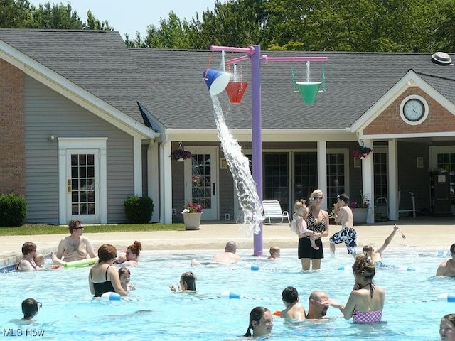 rear view of house with a patio area, an outdoor pool, and a shingled roof