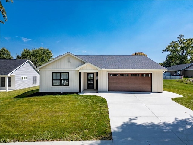 view of front of home featuring driveway, a front lawn, a garage, and a shingled roof