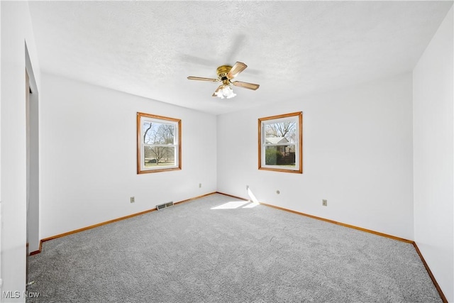 carpeted spare room featuring baseboards, visible vents, a textured ceiling, and a ceiling fan