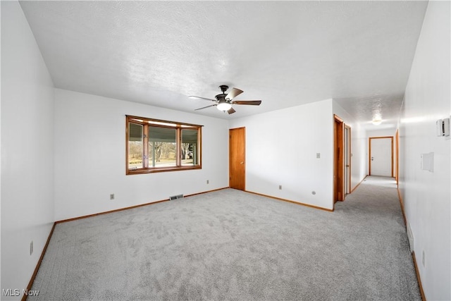 spare room with visible vents, light carpet, baseboards, and a ceiling fan