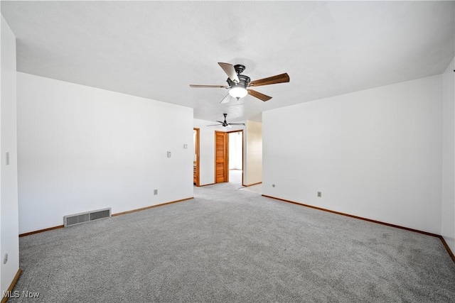 carpeted spare room featuring a ceiling fan, visible vents, and baseboards