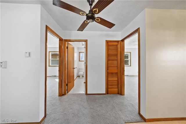 hall featuring baseboards and carpet flooring