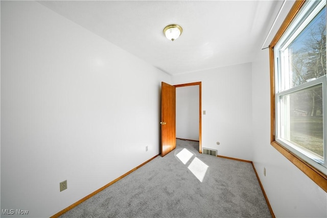 carpeted spare room featuring baseboards and visible vents