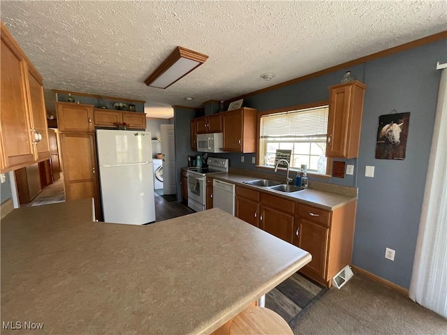 kitchen with visible vents, brown cabinets, a sink, white appliances, and a peninsula