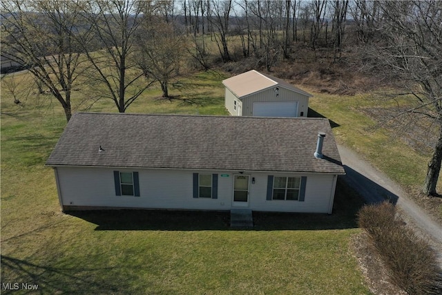 view of front facade with driveway, a front yard, a detached garage, and an outdoor structure