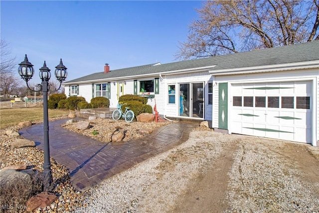 ranch-style house featuring driveway, a chimney, and an attached garage