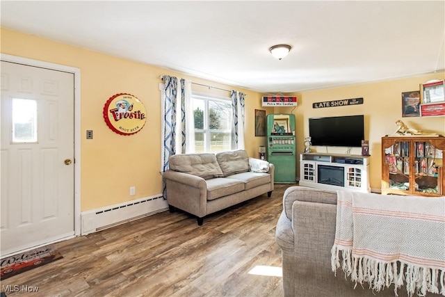 living area with a baseboard heating unit, baseboards, and wood finished floors