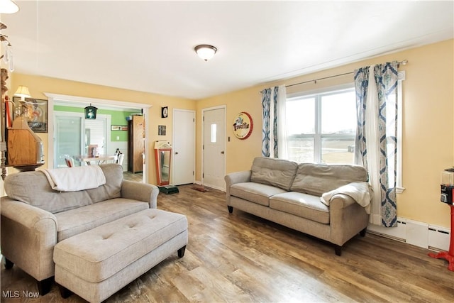 living area featuring light wood finished floors, baseboard heating, and baseboards