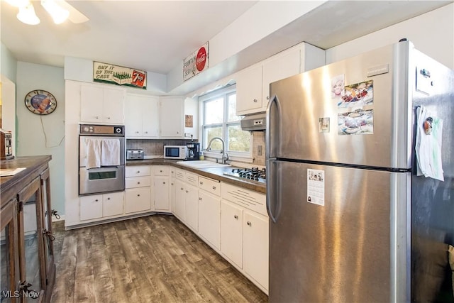 kitchen with dark wood finished floors, a sink, white cabinets, appliances with stainless steel finishes, and backsplash