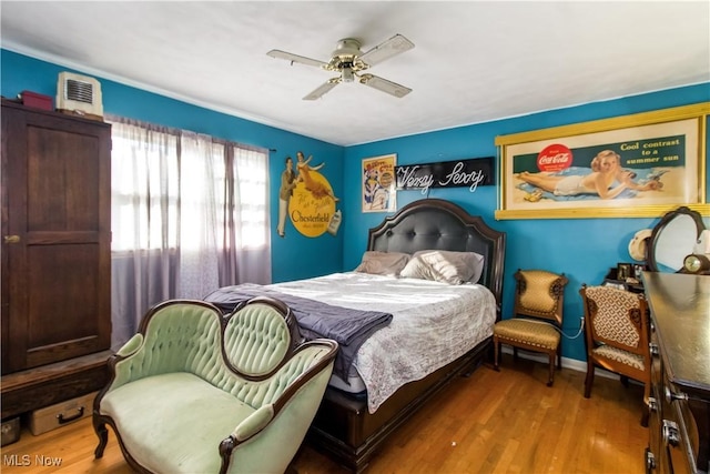 bedroom featuring visible vents, baseboards, ceiling fan, and wood finished floors