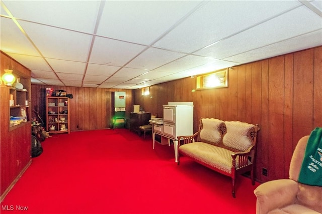 living area featuring wood walls and a paneled ceiling