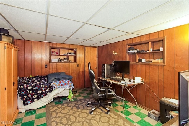 bedroom featuring tile patterned floors, wooden walls, and a drop ceiling